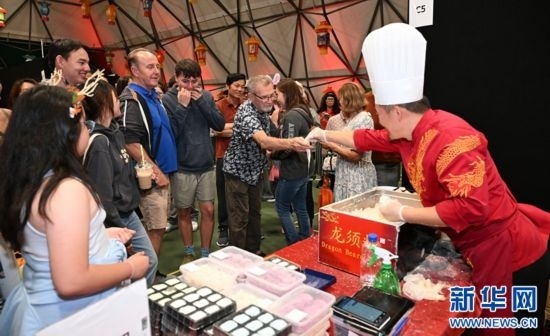 圖為游客在燈節(jié)現(xiàn)場(chǎng)購(gòu)買(mǎi)小吃。（圖片由奧克蘭中國(guó)文化中心提供）