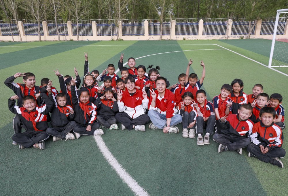 4月23日，在新疆克州阿圖什市哈拉峻鄉(xiāng)謝依特小學(xué)，支教教師王俊文（中左）、李軻凡（中右）和學(xué)生在一起。