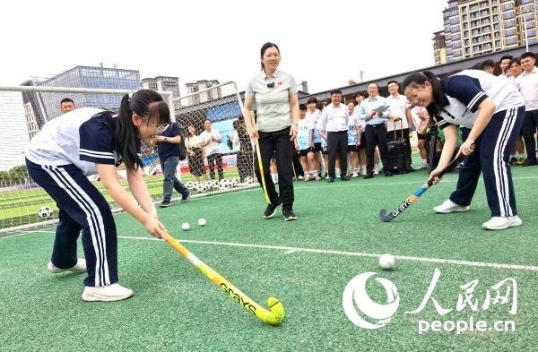 陳朝霞（中）指導(dǎo)學(xué)生體驗曲棍球。 人民網(wǎng)記者 楊磊攝